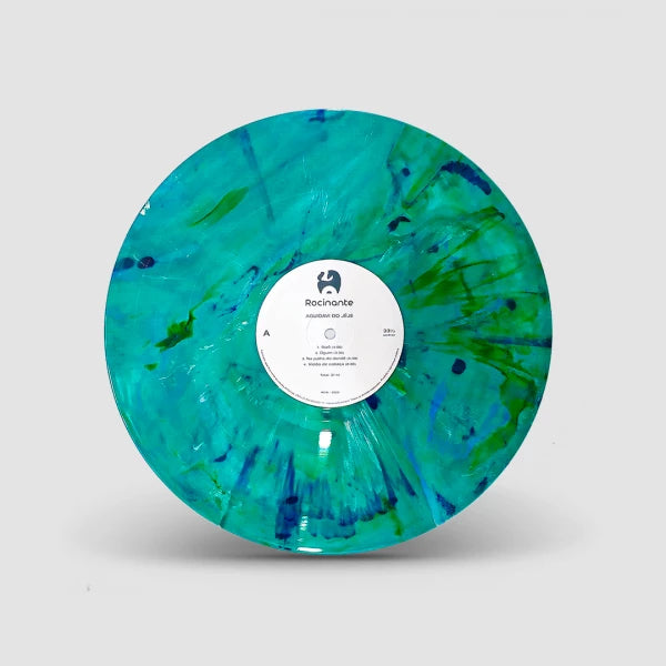 Disco de vinil verde marmorizado do álbum “Aguidavi do Jeje” do grupo Aguidavi do Jeje, com acabamento translúcido em tons de verde, azul e turquesa e rótulo central branco da Rocinante, isolado sobre fundo neutro (disco de vinil).
