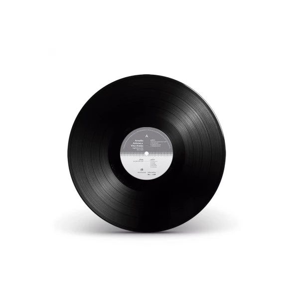 Disco de vinil preto do álbum “Lágrimas no Mar” de Arnaldo Antunes e Vitor Araújo, com rótulo central cinza e branco e sulcos visíveis na superfície, isolado sobre fundo neutro (disco de vinil).