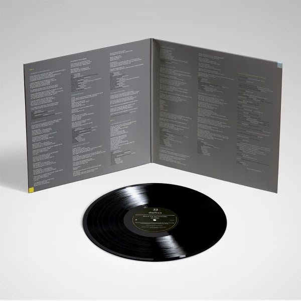 Parte interna do gatefold de Behind The Tea Chronicles com letras das músicas distribuídas em painéis cinza, tipografia minimalista e disco de vinil preto posicionado à frente da embalagem aberta.