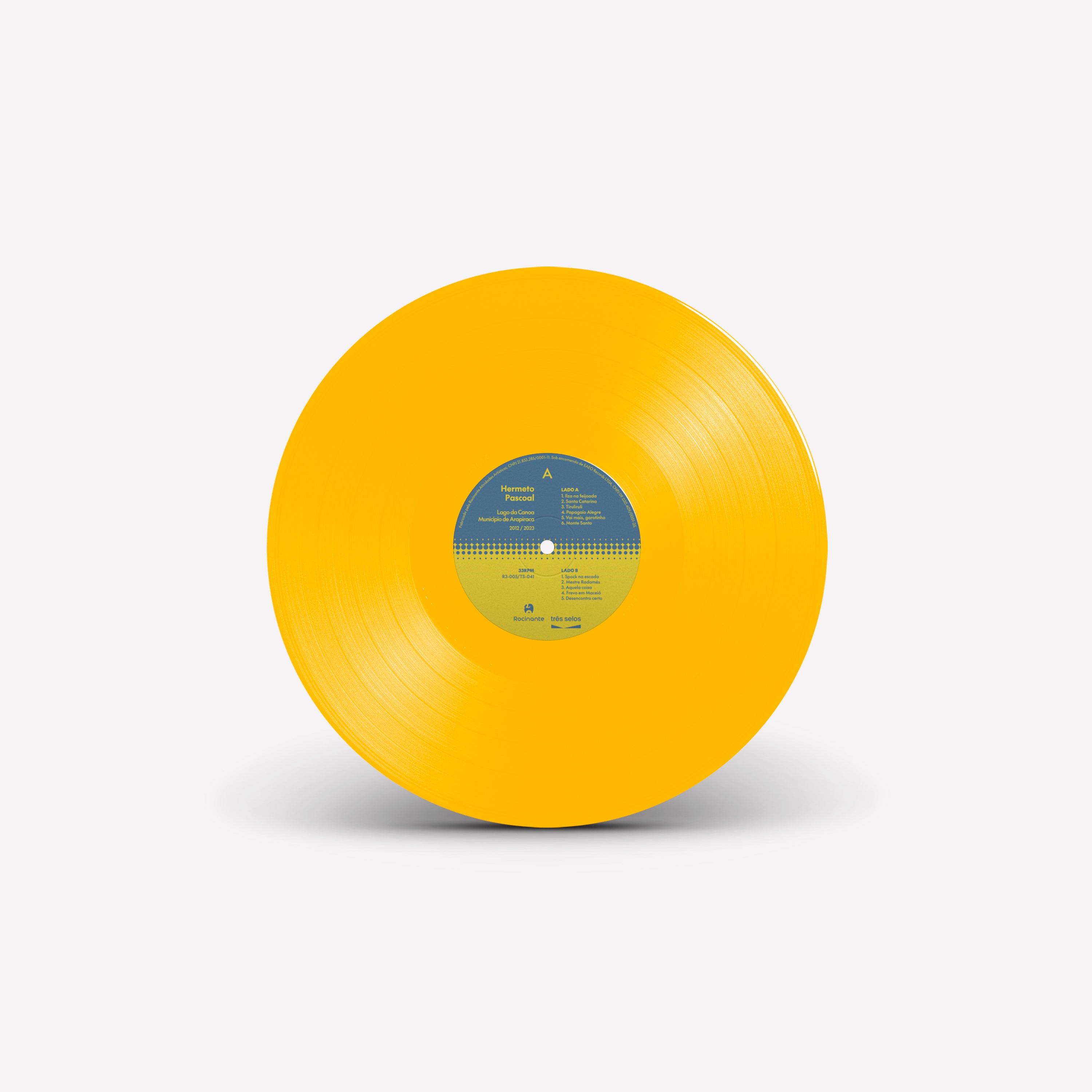 Disco de vinil amarelo do álbum Lagoa da Canoa, Município de Arapiraca de Hermeto Pascoal com rótulo central em azul e amarelo contendo informações das faixas (disco de vinil).