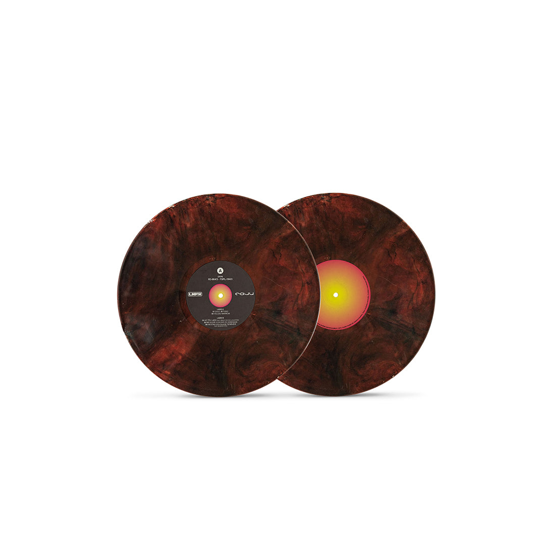 Dois discos de vinil da edição de Caju, de Liniker, com efeito marmorizado em tons escuros de marrom, vermelho e preto. Os discos aparecem sobrepostos sobre fundo branco e possuem selos centrais diferentes, um preto e outro em degradê rosa e amarelo.