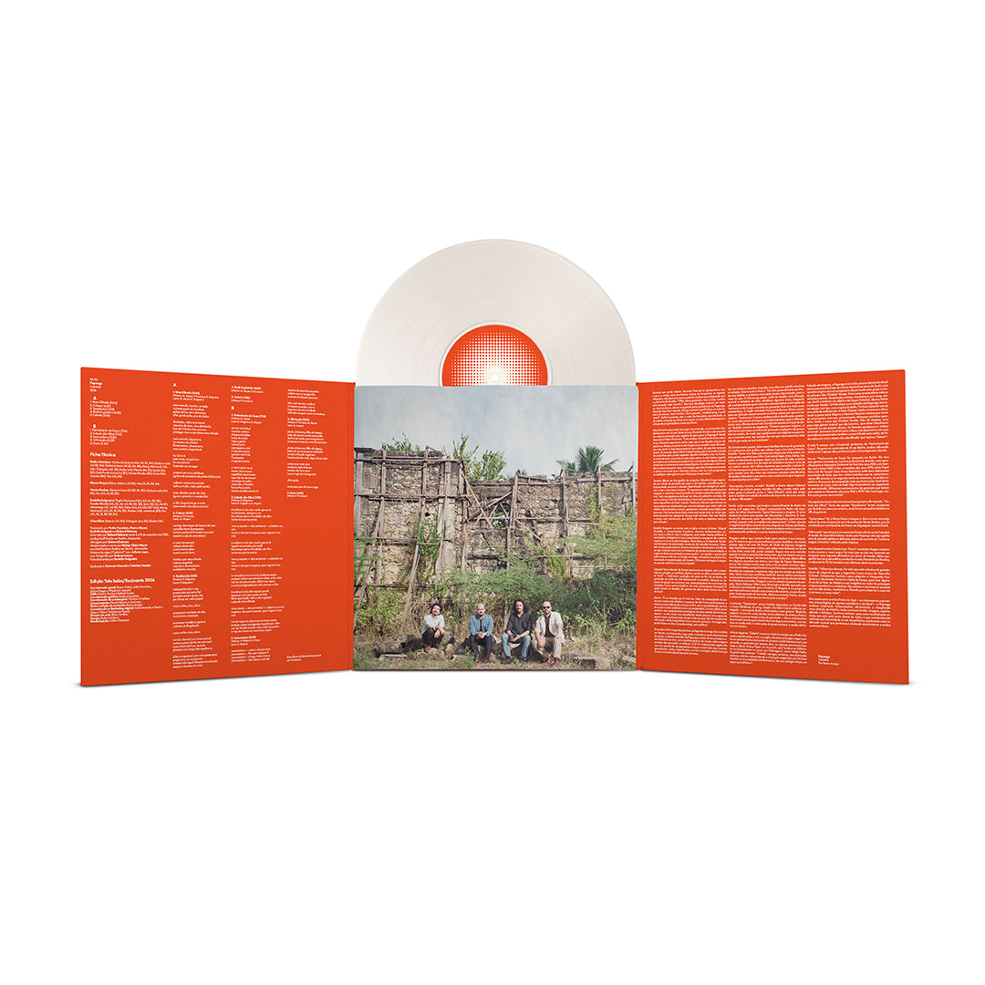 Encarte interno aberto da edição em vinil de Celestial, da Papangu, com fundo laranja e textos impressos em branco distribuídos em várias colunas. O painel central apresenta uma fotografia da banda sentada diante de uma estrutura de madeira e pedras em uma área de vegetação, enquanto o disco branco translúcido aparece parcialmente acima do encarte.